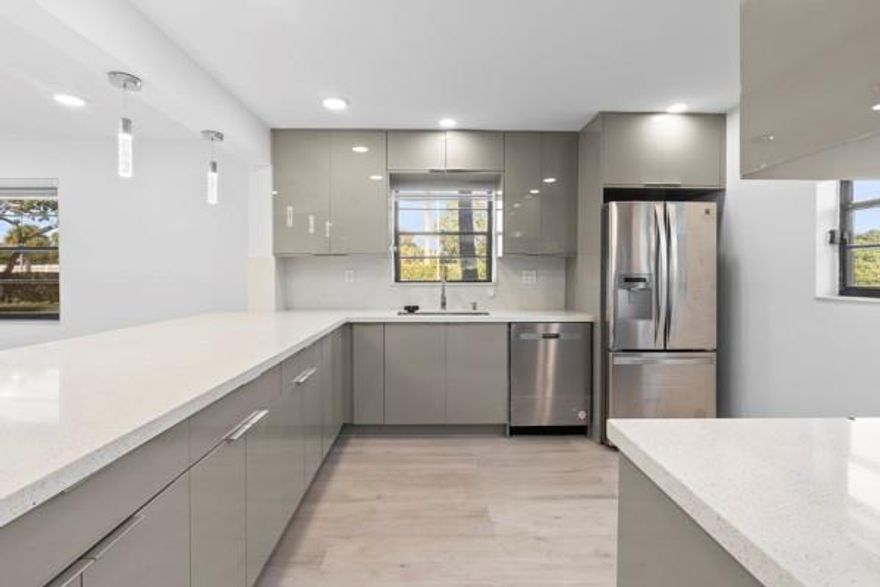 STUNNING, FULLY REMODELED FIRST-FLOOR CONDO WITH LUXURY FINISHES!This one-of-a-kind unit boasts a gorgeous open-concept design with a quartz island and extended bar area, complemented by stainless steel appliances. High vaulted ceilings with LED flush lighting illuminate the main living areas, creating a bright and spacious feel. Enjoy the convenience of a separate laundry room with full attic access, a dedicated office space, ample storage, and sleek quartz countertop Elegant flooring flows seamlessly throughout the home adding a designer touch.