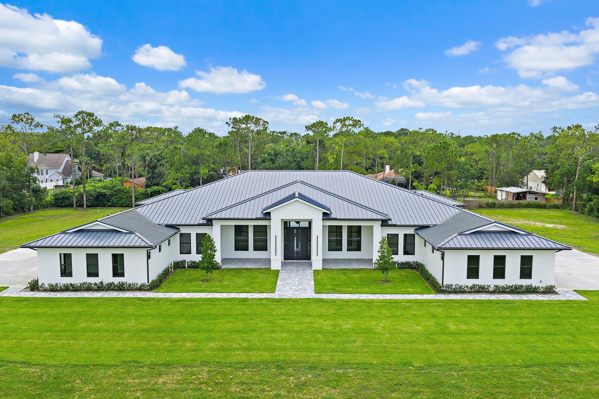 Brand-new construction offering over 8,200 sq ft of air-conditioned living space, 10,900+ total sq ft, and an unmatched level of craftsmanship in Jupiter Farms. Set on 2.5 private acres with no HOA, this one-of-a-kind estate blends modern elegance with thoughtful design, built for both everyday luxury and large-scale entertaining.The main residence features 5 bedrooms, 7 full bathrooms, 2 half baths, and soaring ceilings ranging from 10 to 16 feet. Every inch is finished with premium materials; 48'' x 48'' porcelain tile, level 5 drywall, 8' solid-core doors, and custom built-in closet systems. The gourmet kitchen is outfitted with two Samsung bespoke refrigerators, dual electric ranges, pot filler, 10-foot cabinetry, and a walk-in pantry. A spacious wet bar with a mini fridge and