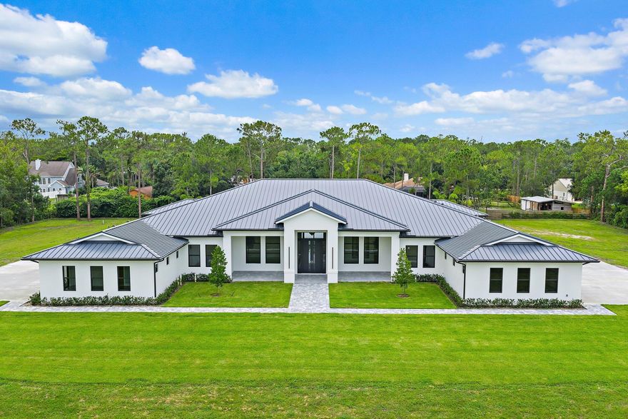 Brand-new 2025 luxury estate on 2.5 acres in Jupiter Farms. Offering 8,230 sq ft of living space + guest house, 6 bedrooms, 8 full & 2 half baths, and over 10,900 total sq ft under roof. Built with uncompromising quality: steel-reinforced CBS construction, impact glass, charcoal metal roof, and foam insulation. Interiors feature 48x48 marble-look tile, soaring 10-16 ft ceilings, custom closets, and level 5 finishes. Gourmet kitchen with dual refrigerators, double ovens, pot filler, wet bar, and 10' cabinetry. Resort-style pool with 6,250 sq ft marble deck, summer kitchen, sauna, gym, billiards, media room, and wine cellar. Guest house with full kitchen & living. Horses permitted, no HOA. A rare opportunity for modern luxury on acreage in Jupiter.