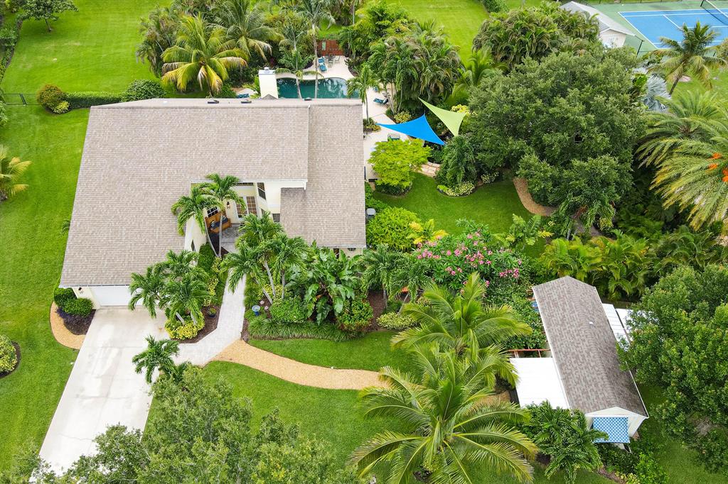 1 acre plus lots are hard to come by, even more so are those with a perfect balance of privacy, land space, low HOA, and desirable location in Palm Beach Gardens. This 3 bedroom CBS home with den and 1 bedroom cottage is move-in ready. A 1-story home with 20-foot vaulted ceilings, open kitchen, split bedroom layout, skylights, oversized master bedroom with a loft and walk-in closet. Master bathroom has a custom vanity, updated walk-in shower, free-standing soaking tub, and bay window. The sellers went above and beyond adding smart home tech inside and out. The 1.1 acres hold a stunning pool, full 1 bedroom cottage, fully fenced backyard, koi pond, and diverse landscaping. A huge hobby room adds versatility, as it can be used as a 4th bedroom, den, office...
