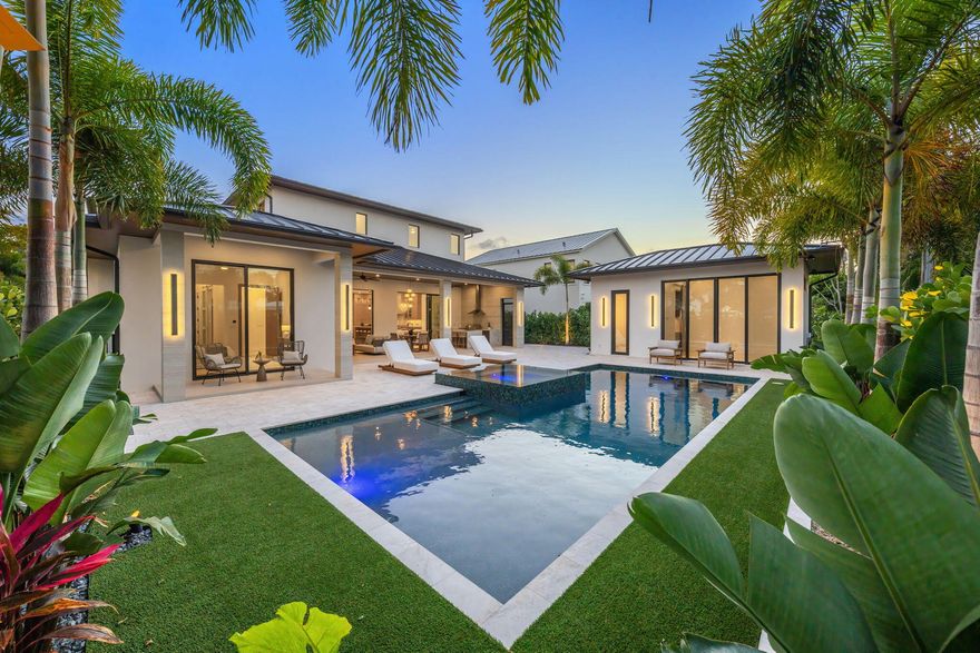 Welcome to 247 Seville Road — a newly completed modern-coastal residence in SoSo, custom built by Spyglass Development, offering a rare combination of architectural detail, scale, and resort-style living on an oversized 11,285 SF lot just east of Olive Avenue. Offering 6,378 total square feet with 5,112 SF of living space, the main residence includes 4 bedrooms plus an office, 4 full baths and 1 half bath, a double garage, and elevator across 4,785 SF. A detached 327 SF cabana/flex suite with full bath, outdoor shower, and Sub-Zero under-counter drawers functions as a fifth bedroom, guest suite, private office, or fitness studio.  A porcelain-travertine façade and 10-foot entry door open to interiors defined by 11'6" ceiling heights with 12-foot coffered accents, 9-foot interior doors on the main level, 10-foot exterior sliders, 48x48 Italian porcelain flooring, and a floating white-oak and glass staircase. Rift-cut white oak cabinetry, fluted wall detailing, and integrated architectural millwork carry throughout the home. The chef's kitchen features Nika Quartzite countertops, a 12' x 5' island, Sub-Zero refrigeration towers, a 48" Wolf 8-burner range, walk-in pantry, and a custom rift-cut oak bar with Sub-Zero wine tower. The first-floor primary suite includes oak flooring, dual custom closets, and a spa-style bath with dual 16-foot showers, soaking tub, and dual water closets. A dedicated office with oak flooring and American black walnut cabinetry is also located on the main level. The second floor offers 10-foot ceilings, a loft with built-ins and Sub-Zero beverage center, secondary laundry, and three en-suite bedrooms including a VIP suite. Bathrooms are finished with imported Spanish porcelain tile and custom cabinetry. Upper-level interior doors are 8 feet. Twelve-foot-wide bypass stackable doors open to a covered loggia with travertine fireplace wall, summer kitchen with grill, sink, and refrigerator, cypress cabinetry, remote-controlled screens, designer lighting, and aluminum tongue-and-groove ceiling in a wood-look finish. The 37 x 16 saltwater pool with sun shelf and 9 x 9 spa are set within professionally designed tropical landscaping. Additional features include a whole-house generator, engineered site drainage system, concrete subfloors for structural and sound stability, EV pre-wire, and an air-conditioned double garage. Located on a quiet, tree-lined street east of Olive Avenue, the residence is moments from Intracoastal Waterway, Summa Beach, Flagler Drive bike path, marinas, golf, dining, Palm Beach Island, downtown West Palm Beach, and Palm Beach International Airport. FPL is currently undergrounding neighborhood power lines. All measurements and information are deemed reliable but not guaranteed. Buyer to independently verify.