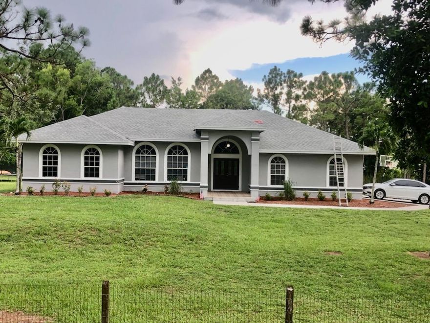 Brand new Roof being installed. This beautiful home in The Acreage has 1,5 Acres in land that can be built. No HOA, it be rented out. Located at the end of the street and next to a canal for great privacy. Plenty of room for a pooI, 4 Beds 2 Baths with extra living space. Optional Garage, this home has two large living areas and an updated kitchen with granite counter tops. Split bedroom floor plan with large master bedroom and master bath featuring brand new walk-in shower, dual vanities and large soaking tub.  Three of the other bedrooms share at bath with dual vanity.  There's a screened-in patio to enjoy the outdoors with an outdoor kitchen/grill area.   Property is also fenced for additional privacy. House just painted on interior and just  Installed mosquito system. Water tank 2020 ac 2017 This is a must see!