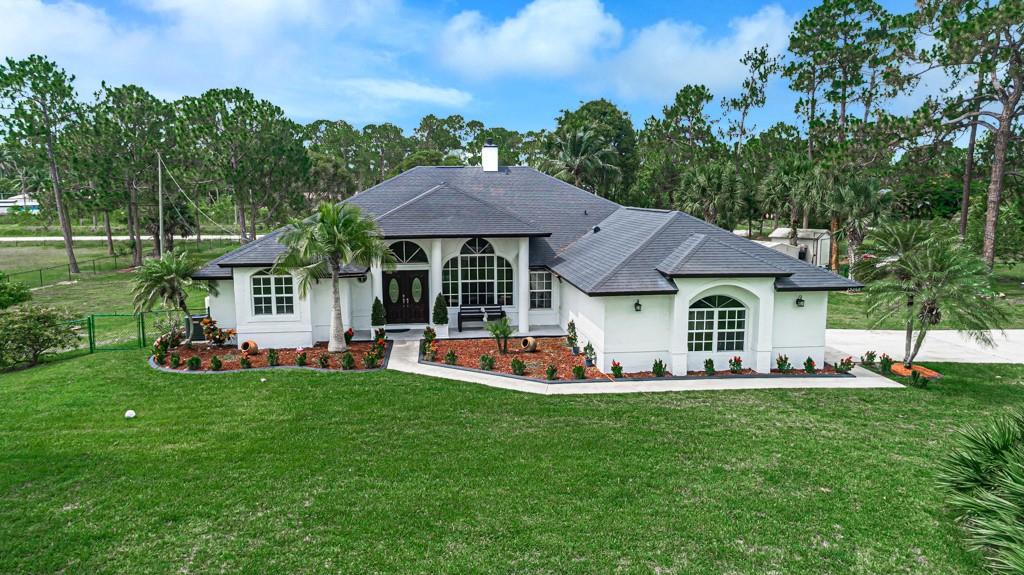 Over 2 Acres in a Highly Sought-After Area of The Acreage! This beautifully renovated single-family home offers nearly 2,600 sq. ft. under A/C,featuring 4 beds, 2.5 baths, plus a den/office. The open floor plan showcases high ceilings, a cozy fireplace, and a formal dining room alongside a sunny breakfast nook.
The modern kitchen boasts top-of-the-line black stainless steel appliances, including a new cooktop, while the bathrooms have been tastefully updated. The home has two separate A/C units, a tankless water heater, and is completely tiled throughout. Situated on a property that runs street-to-street and borders a canal, this estate is fully fenced and cross-fenced with a double concrete/paved driveway offering parking for up to 20. Finished garage/bonus bedroom and two storage sheds.