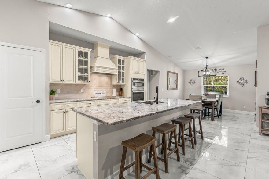 Welcome to this exceptional 2022-constructed CBS single-story home, beautifully positioned on an elevated 1.14-acre lot in The Acreage. Offering 4 bedrooms and 2 full baths in a desirable split-bedroom layout, this residence combines modern construction with over $25,000 in thoughtful builder upgrades. The open floor plan is enhanced by vaulted ceilings, abundant natural light, impact windows and doors, and upgraded Level 2 24x24 tile flooring throughout -- including bedrooms in lieu of carpet. Underground electric service adds both aesthetic appeal and reliability. The gourmet kitchen was extensively upgraded and features premium cabinetry (42'' uppers), glass cabinet accents, a custom cabinet layout with built-in wine cooler accommodation, Level III White Spring granite countertops, Mediterranean Ivory tumbled backsplash extending to the upper cabinets, upgraded GE wall oven/microwave combo, 30" cooktop with Broan hood vent, and a spacious center island ideal for entertaining. Designer details continue throughout the home with brushed aluminum interior trim, upgraded hardware and door handles, black plumbing fixtures and accessories, and elevated tile selections including a Level 3 listello accent in the master bath. The spacious owner's suite offers a large walk-in closet and a beautifully appointed bath featuring dual sinks, soaking tub, and separate shower with upgraded fixtures. Additional features include a whole-home water filtration system and a two-car garage. The Acreage is known for its expansive acre-plus lots, convenient access to Downtown West Palm Beach, Westlake, Palm Beach Gardens shopping, and Palm Beach International Airport -- and best of all, no HOA restrictions. Bring your pets, RV, boat, trailer, and all your toys.