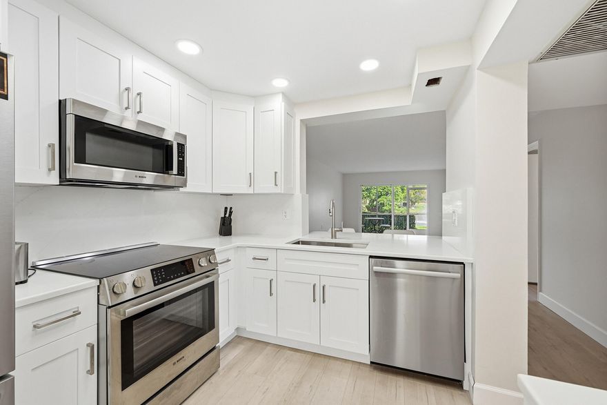 Beautifully remodeled 2BR/2BA condo in Wynmoor Village with serene lake and fountain views. Features a modern white kitchen with newer cabinets, quartz countertops, and stainless steel appliances. Both bathrooms are renovated with new vanities and updated showers. Waterproof vinyl flooring throughout and freshly painted interior. The second bedroom was expanded by removing a wall, creating a large suite with its own bath and extra closets. High-impact windows and doors. Prime location near clubhouse, walking distance to tennis and pickleball courts. Move-in ready!