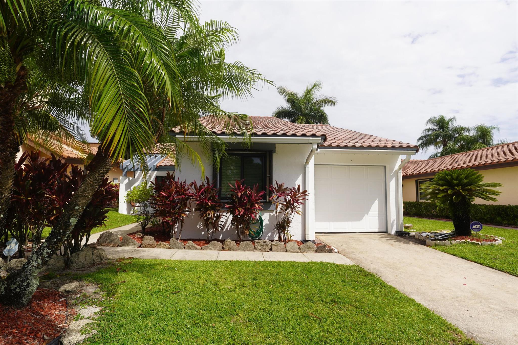 This CBS 2-bed, 2-bath home with garage sits at the end on a quiet street and offers strong bones with room to upgrade. Features include a desirable split floor plan, spacious primary suite with walk-in closet and patio access, and new vinyl flooring in both bedrooms. One bathroom has been recently re-tiled; the other remains original but has a vanity with a granite countertop, offering a blank slate for updates.Enjoy peaceful outdoor living with both covered and open patio areas, a fully fenced backyard, and mostly impact windows--including two out of three impact-rated sliders. A/C replaced in 2019; roof is original. Community includes a pool, and the HOA covers lawn care for easy maintenance. Ideal for buyers looking to customize and add value.