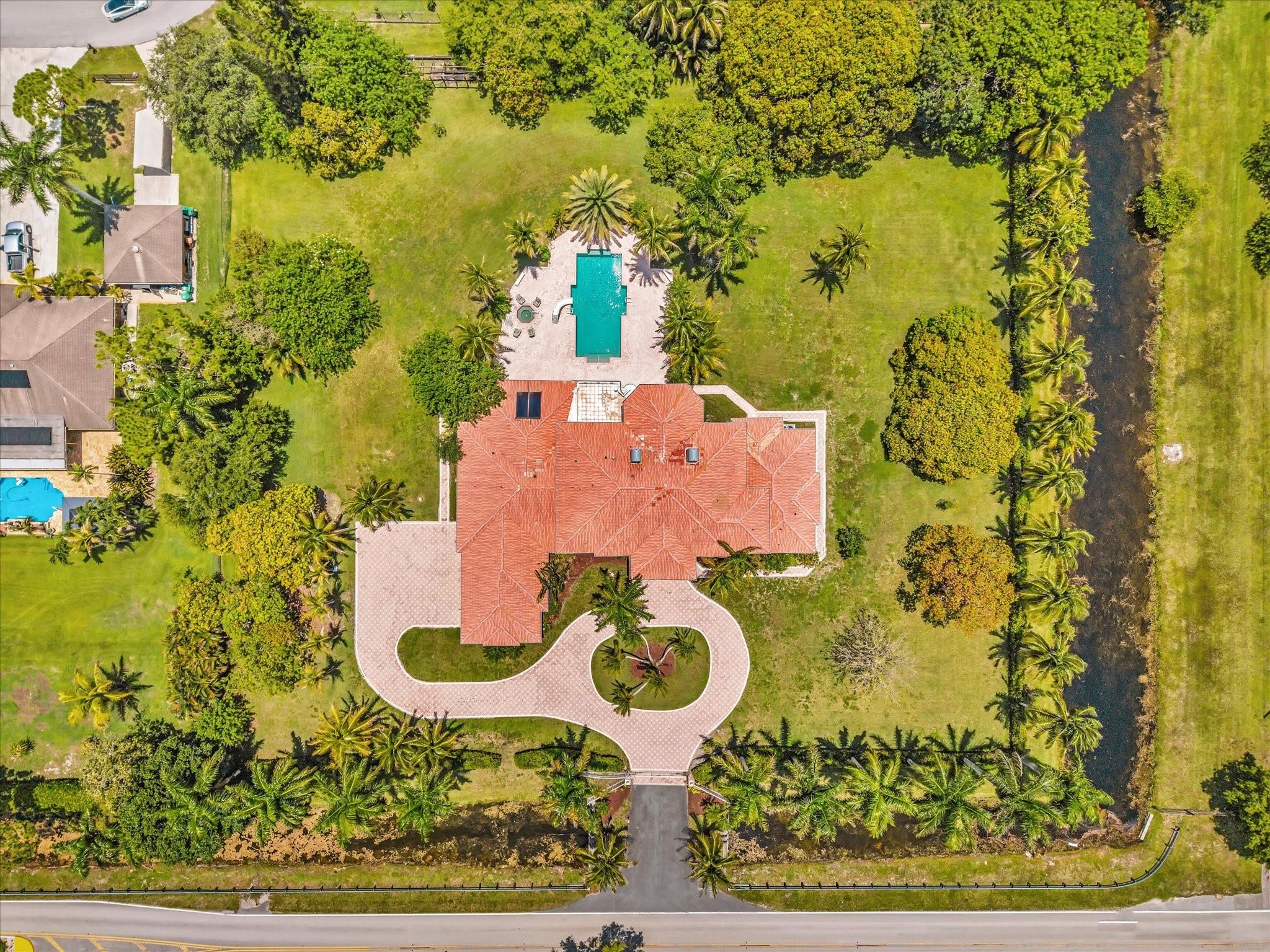 Set on over two acres, this spacious two-story home offers 9 bedrooms, 8.5 bath and 7,772 sq ft of living space. The layout features an office, dining room, and a 2-bed, 2-bath suite with its own living area and potential kitchen — perfect for multigenerational living or a private guest retreat. The large master suite includes his and her closets and a balcony overlooking the backyard pool, and separate hot tub. A 4-car garage ensures ample space for vehicles and storage. This home presents a rare chance to transform it into a modern retreat or a custom family compound in a sought-after Davie location.
Check out the virtual video to see what the home could look like. The renderings in the video are for illustrative purposes only and does not reflect the current condition of the home