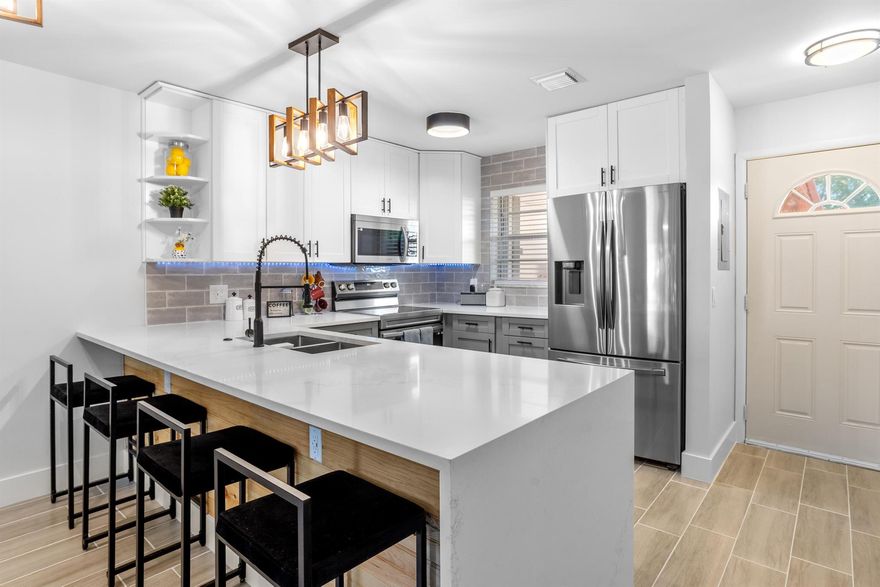 Discover modern living at its best in this meticulously renovated 2 bedroom 2 bathroom condo located in desirable Active Adult 55+ Community of Greenway Village in Royal Palm Beach, FL/ with a recently renovated interior, this condo boasts a tastefully remodeled kitchen with a Quartzite waterfall peninsula, featuring a contemporary open-concept design achieved by removing a wall for more open feel. The Kitchen features all new cabinets with soft close drawers, and Full size Samsung Appliance package with oven/Air fryer and smart appliances. Kitchen sink features touchless faucet. All new LED light fixtures for energy efficiency. This modern industrial feel extends throughout, creating an atmosphere of style and comfort.  Both baths remodeled and have Bidets and LED mirrors.