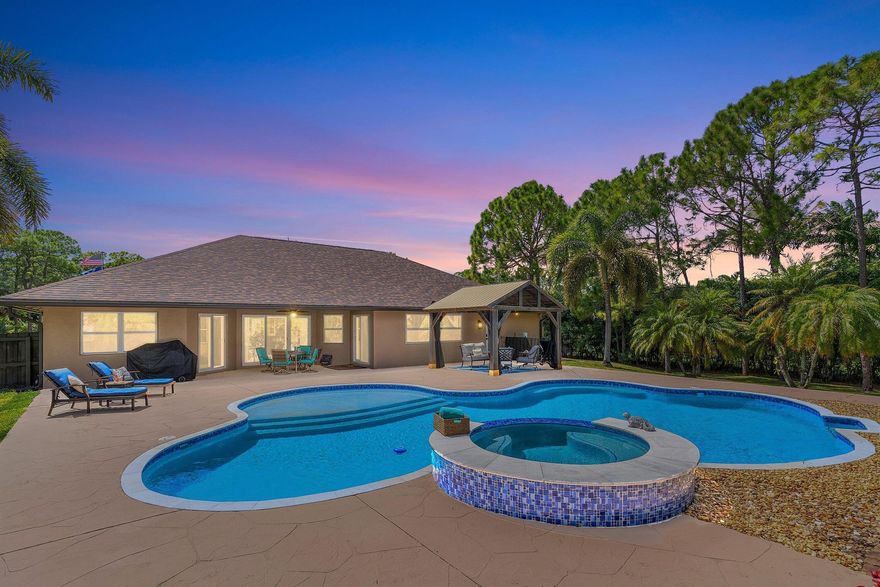 WELCOME HOME This well appointed gem is resting on a premium 1.47 acre lot and boasting 4 bedrooms, 3 full baths, enormous 40' x 25' sparkling saltwater and heated pool with waterfall spa, 2 car attached garage and a spectacular (1500 sqft) 2021 built shop, upgrades and updating galore, hurricane impact windows and doors, 2025 roof, paved road coming before 2026 and this beauty is in a superb location! ENTERING the decorative circular driveway you will discover that this rare find is resting on a high and dry fully fenced private corner lot with no pond and over 500' of waterfront. The grand covered entry brings you inside the double front doors where you are greeted by 13' vaulted ceiling, rounded corners, extensive millwork throughout and solid core doors, windows galore and (CLICK)