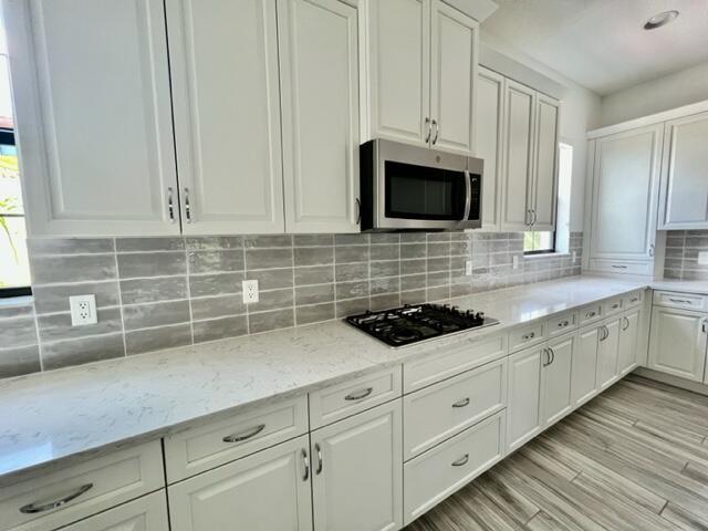 Best location! Just steps from Alton Town Center in this very desirable luxury ''Alton'' community. This professionally managed luxurious 3-story townhome is very spacious with modern updates that feature; large open kitchen with quartz countertops, large island, custom cabinetry and stainless-steel appliances. The kitchen is open to a large living/dining space and custom flooring. Additional features include; hurricane impact glass, natural gas and a 2-car attached garage with additional guest parking. Alton is just minutes from the beach and from the Gardens Mall. Enjoy the green space by stepping out the front door or from one of its two balconies. Enjoy the exclusive use of the Alton clubhouse complete with fitness center, basketball courts, tennis and pickleball courts,