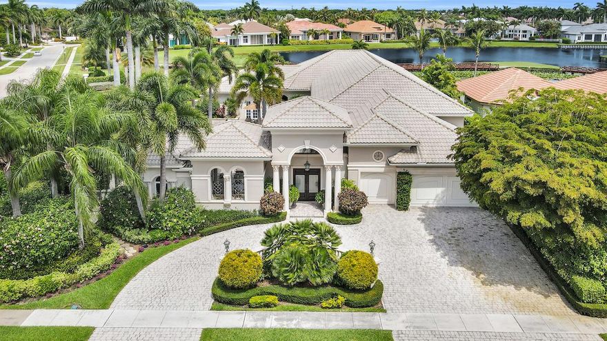 One-of-a-kind breathtaking vistas of the shimmering lake and golf course views are the salient features of this custom-built estate. Approaching your private courtyard oasis, the grandeur of resort-style living is amplified by an impressive sunfilled patio, oversized pool, and spa. Verdant tropical landscaping is viewed in the distance, where no other homes surround to the south, showcasing vast panoramic lake and golf course views. Entering the grand living room, inviting elements of the seated wet bar, fireplace, and soaring ceiling details are enhanced by the peaceful views and charming bridge over the lake as the backdrop through the windows where stellar sunsets may also be viewed. The open concept of this home exudes practicality and elegance when entering the generously ->