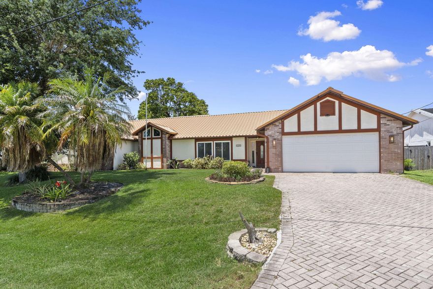 Set on an oversized double lot with direct canal and ocean access, this 4-bedroom, 3-bath home delivers 2,912 square feet plus an attached private suite complete with its own bedroom, full bathroom, kitchenette, office, private entrance, and dedicated garage. Inside the main residence, the kitchen has been completely updated, white shaker cabinets, granite countertops, an expansive center island with ample seating, stainless appliances, and wine cooler. The layout flows seamlessly into two separate living areas and a dedicated dining space with vaulted ceilings and crown molding throughout. The primary suite has direct pool access and an en suite that earns the word spa: dual vanities, rich walnut cabinetry, granite counters, round mirrors, water closet, and a large frameless glass walk-in shower with designer tile detail. Out back, enjoy a large screened lanai with salt water pool, full summer kitchen, and covered lounge area. The canal frontage extends to a private dock with power, currently setup for a 14ft boat, and covered gazebo. Additional highlights include solar panels (owned), hurricane-impact windows and doors throughout, whole-home reverse osmosis water filtration, central vacuum, metal roof, a fully equipped private cedar sauna, and a paver driveway surrounded by mature tropical landscaping. The Tudor-accented facade and lush canopy give the front of this home striking curb appeal that immediately stands out. Canal access. Double lot. Private in-law suite. Sauna. Saltwater pool. A property designed to offer both luxury and versatility.
