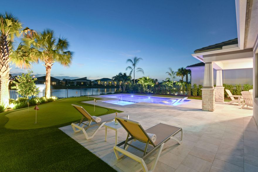 This Riverwalk floor plan in Avondale at Avenir blends modern comfort with a true resort style atmosphere, elevated by a custom heated pool and spa, a private putting green, and wide lake and fountain views that frame unforgettable sunsets. The home's thoughtful layout and premium outdoor amenities create a setting that feels both luxurious and deeply livable. The main level centers around bright, open living spaces where large windows capture the shimmering lake and bring natural light into the great room and kitchen. The kitchen's generous island and abundant counter space make it ideal for gathering, cooking, and entertaining, all while staying connected to the main living areas. A dedicated home office sits toward the front of the home, offering privacy and quiet for work or study.  Its separation from the main living spaces allows for productivity without sacrificing the home's open, airy feel. Upstairs, the loft adds flexibility as a second living room, media space, fitness area, or playroom. The surrounding bedrooms are well proportioned, and the primary suite enjoys the best views in the home. Sunsets reflecting across the lake create a calming backdrop at the end of each day. The outdoor living space is the true highlight. A custom heated pool and spa anchor the backyard, surrounded by ample deck space for lounging and dining. The private putting green adds a fun, functional element—perfect for practicing your short game, hosting friends, or simply enjoying time outdoors. The west facing orientation ensures every evening brings a front row seat to vibrant Florida sunsets, with the lake and fountain adding movement and sound to the setting. Living in Avondale at Avenir enhances the experience even further. The community offers modern architecture, lush landscaping, and access to Avenir's exceptional amenities, including parks, trails, and a resort style clubhouse. Its Palm Beach Gardens location places you close to top rated schools, golf, dining, shopping, and the beaches that define the area's lifestyle. With its custom pool and spa, private putting green, flexible loft, dedicated home office, and serene lakefront setting, this Riverwalk floor plan offers a rare blend of everyday comfort and elevated Florida living.