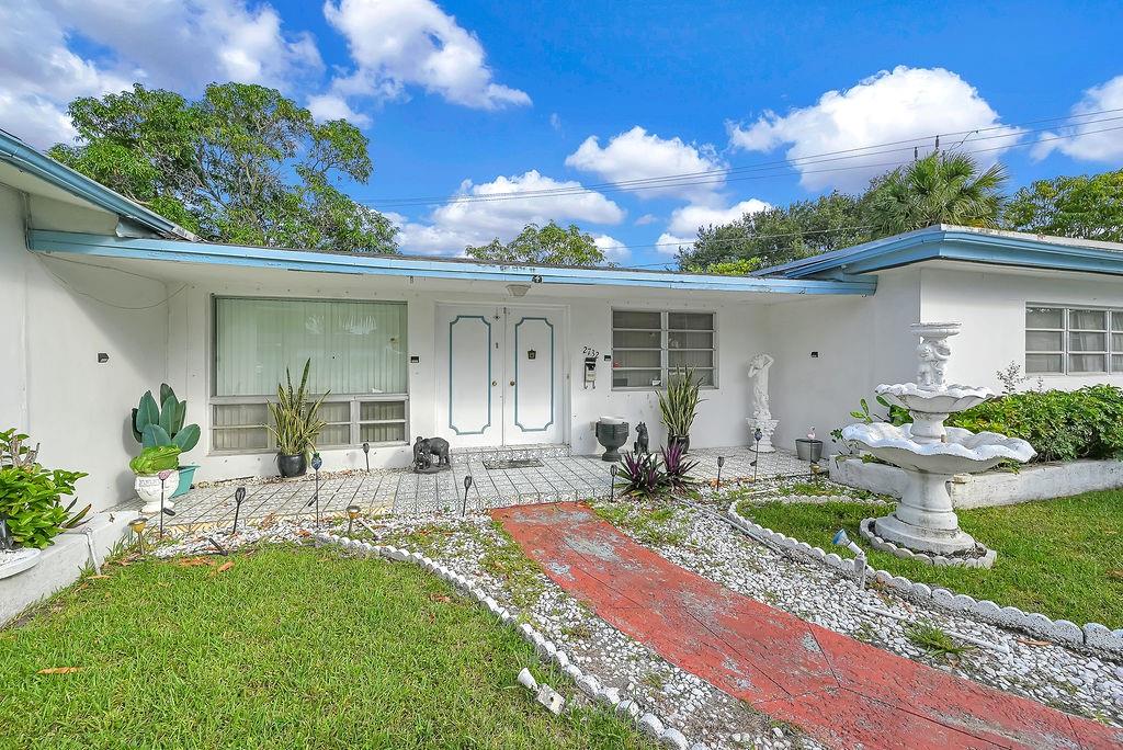 Dream Home Potential in Wilton Manors Westside. This spacious 3-bedroom, 2-bathroom home sits on a generous 9,264 sq ft partial corner lot and offers 2,057 sq ft of living space—plenty of room to customize and expand. A circle driveway leads to a large garage with ample parking. Inside, you'll find tile throughout, a newer A/C, and a large laundry/utility room. The screened-in covered patio overlooks mature mango trees and tropical palms, creating a serene outdoor retreat. With solid bones and great space, it’s ready for your personal touch. With its prime Westside location, this property presents an unparalleled opportunity to reimagine and transform into your dream home.