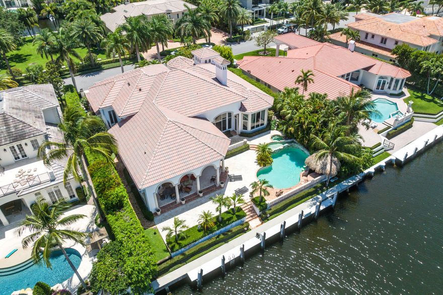 Spectacular waterfront estate in Royal Palm Yacht & Country Club with 5 bedrooms, 6 full baths, and 1 powder room. Situated on 104' of the Butterfly Palm Waterway, this Spanish-inspired home features a large eat-in kitchen, formal dining room, study, equipped bar, and an expansive first-floor main suite. The formal living room has floor-to-ceiling windows opening to the serene pool area and summer room. Additional features include a private deep-water dock, multi-tier heated pool/spa with swim-up bar, and generator.