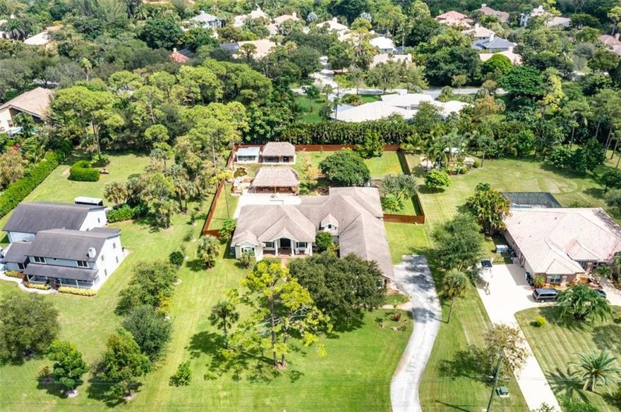 A stunning oasis. Simply a beautiful estate home with farmhouse influences. Sited on one of Parkland's prettiest streets. Impressive curb appeal with a rocking chair front porch/sprawling front lawn/manicured landscape/3 car garage & long drive. The new Jaw-dropping island kitchen is the heart of the home. The spacious primary suite features a sitting area, wood floors & a luxurious spa-like bathroom. Soaring walls of impact windows & glass doors allow for sun-drenched living areas & views of the magnificent pool area & breathtaking outdoors. The backyard is magical & offers an oversize pool w sunning shelf/huge tiki bar with a full kitchen & wood-burning pizza oven/firepits/stable/chicken coop/screen porch with bar/fruit trees/pond with fountain. Large multi/rec room adds to its splendor. If you are looking for a home the whole family can love, this one is for you. This Quintessential Florida home offers stunning indoor/outdoor living areas.  Although it is elegant, it is also a mini-farm within a beautiful up-scale community. You will love the mangoes, avocado, jackfruit, guava, soursop, papayas, and sour orange trees,