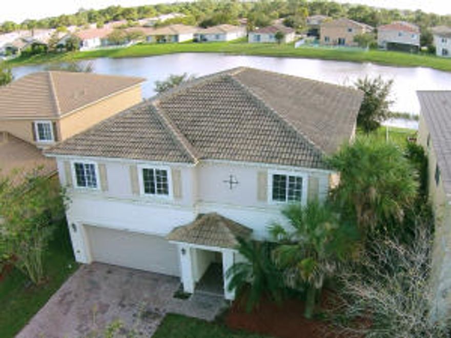 Spacious lakefront 5 bedroom / 3 bath home with over 3000 sq. ft. under air ready for move in. Large master suite with bonus room that can be used as office, den, or theater.  Master bath has tub, separate shower and 2 sinks. Granite kitchen, diagonal neutral color tile throughout first level floor and beautiful upgraded dark wood laminate floors throughout upstairs.  One bedroom and full bath downstairs. Located in Newport Isles, a wonderful gated community with low HOA fees and close to Tradition, Tradition Hospital, and I-95. Community offers manned security, 11 lakes, 2 swimming pools, game room, gym, tennis courts, basketball courts, playgrounds, sand volleyball, walking paths and well-appointed common areas.