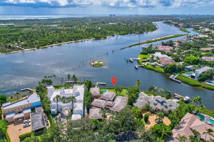 Elevate your lifestyle with this exceptional contemporary residence in Admirals Cove, boasting 180 feet of direct Intracoastal frontage. Crafted by luxury home builder Shapiro Pertnoy in 1999, this 6,400 sq. ft. masterpiece showcases Wendell Castle front doors, a sun-drenched living room, and a modern kitchen featuring Downsview cabinets, a Wolf range, and SubZero and Miele appliances. The first-floor primary bedroom oasis includes a sitting room, two bathrooms, and two offices. A second bedroom with an en-suite bath completes the main floor. A detached guest house provides additional living space. Outdoors, relish in a boater's paradise with a private dock, boat lift, and a pool in the oversized backyard. Seize the opportunity to redefine luxury living in this sought-after location.