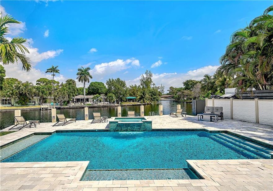 Magnificent waterfront pool home located on quiet cul-de-sac within walking distance to Wilton Drive! This newer custom home features soaring coffered ceilings, open floor plan with 3 way split bedroom plan. Huge open kitchen with 48" Thermador refrigerator, double wall ovens, built in microwave, induction cook top, tons of custom wood cabinetry, and rich thick stone surfaces. Other upgrades and unique features include  24x24 Creme marbe marfil floors throughout, 2 jetted tubs in en-suite baths, spacious bedrooms, custom built-ins, huge heated salt-water pool with spillover spa, marble lanai, and 65' concrete dock overlooking beautiful meandering Middle River.