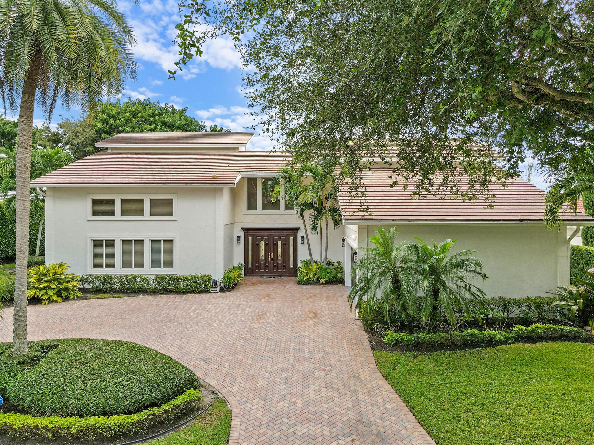 A private sanctuary on an oversized homesite, this custom residence blends timeless architecture with resort-style comfort. Beyond the manned gate, a circular paver drive leads to a light-filled 4BR/3.5BA home with 4,661 SF of gracious living--formal living and dining, a generous family room, and a wet bar--all beneath volume ceilings with a fireplace and French doors opening to the pool. Freshly painted interiors provide a crisp, move-in-ready backdrop.within 10 minutes to palm beach and PBI airport