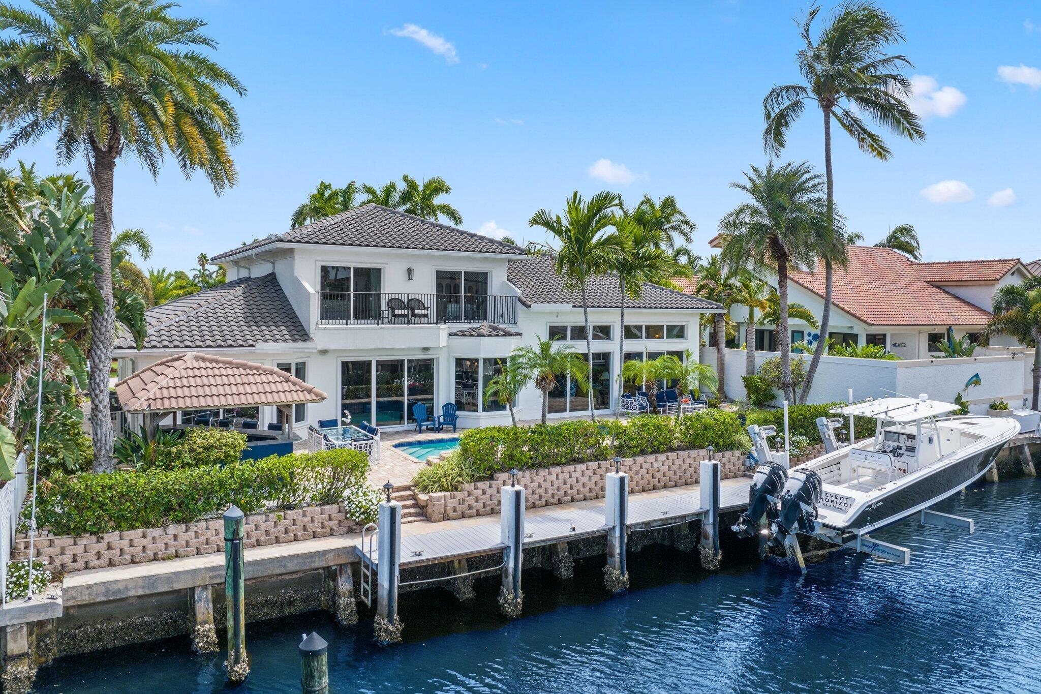 Experience the pinnacle of waterfront luxury in Delray's coveted Tropic Isle. 5-bedroom 5.5-bath deepwater estate boasts 90 feet of prime waterfront on an extra-wide canal, offering effortless ocean access for the boating enthusiast. Inside, refined elegance meets warm sophistication. The great room showcases soaring coffered ceilings, gas fireplace and sweeping water views. An entertainer's dream kitchen features 2 pantries, generous granite island, rich cherry cabinetry, Jenn-Air french door fridge, double Bosch wall oven, breakfast area, wrap-around bar and separate wet bar--perfect for hosting everything from intimate dinners to lavish soirees. First-floor primary suite is a private sanctuary with custom oversized walk-in closet, in-suite washer/dryer and spa-inspired bath complete