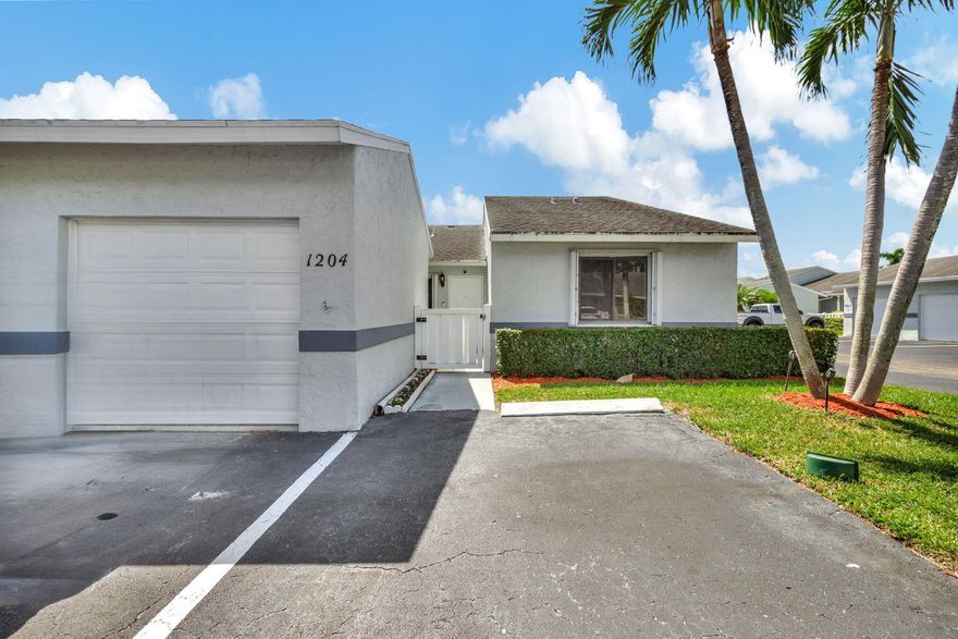 A newly painted, 1,384 sqft corner villa featuring 3 bedrooms and 2 bathrooms, plus a one-car garage equipped with a new electric hurricane-rated door. This home is situated in a centrally located, active adult community (55+). The property boasts quartz countertops in a recently remodeled, open-concept kitchen featuring all-new appliances. It features a mix of tile and wood flooring throughout, a spacious master bedroom with a fully renovated en-suite bathroom—complete with tempered glass shower doors—and a walk-in closet, as well as two additional, equally spacious bedrooms. Outside, you will find a screened-in covered patio with a laundry area, along with a lovely backyard. The home is equipped with a generator hookup and hurricane shutters for storm protection.  The HOA fee covers building insurance, water, cable TV, internet, sewer service, trash collection, and maintenance of both the landscaping and common areas. Additionally, the community offers two heated swimming pools, access to a clubhouse, tennis courts, and a banquet/meeting hall. Conveniently located close to shops, restaurants, beaches, and PBIA airport. A truly beautiful property!