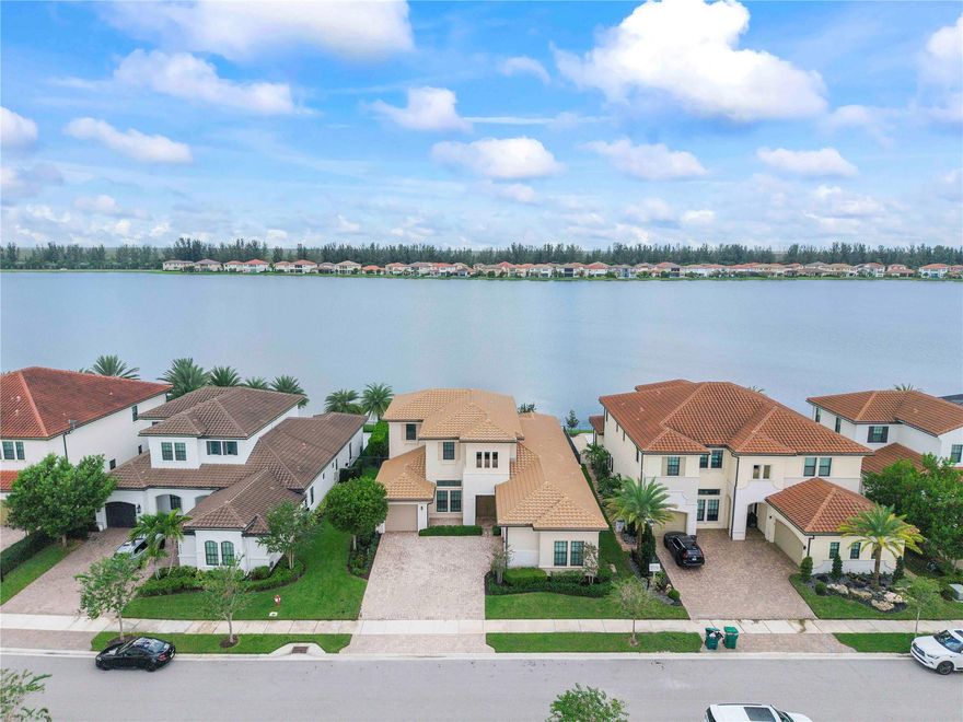 Located in Parkland Bay with stunning west-facing lake views and picture-perfect sunsets! This expansive 4,200+ sq ft home features 4 bedrooms, an office, loft, and 3.5 baths. The primary suite has a spa-style bathroom with soaking tub and large shower, and custom built walk-in closets. Downstairs also offers an office and powder room, while upstairs includes a loft, 3 bedrooms, and 2 baths—one en-suite. Situated on an oversized, fenced lot with impact windows/doors and summer kitchen-ready setup. Interior highlights: chef’s kitchen with double quartz island, GE Monogram appliances, high-gloss tile downstairs, wainscoting, wood floors upstairs, upgraded rails, flat walls, and custom closets throughout. Enjoy resort-style amenities: heated pool, gym, tennis, playground & A+ schools!