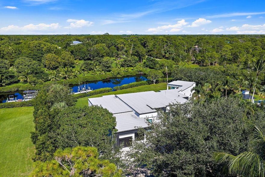 A rare fusion of privacy, precision, and architectural artistry, this minimalist modern masterpiece by Riverside Building & Design rests on over two acres along the North Fork of the Loxahatchee River. Designed to blend with its natural surroundings, it features clean lines, expansive glass, and seamless indoor-outdoor living with tranquil river views throughout. Highlights include a chef's kitchen with luxury appliances and custom cabinetry, a resort-style pool and spa, and a covered summer kitchen for effortless entertaining. A private dock with 16,000-lb lift offers direct access to the Intracoastal and Atlantic Ocean. With sleek design and timeless tranquility, 8309 SE Rivers Edge stands as one of Jupiter's most distinctive and private new waterfront estates.