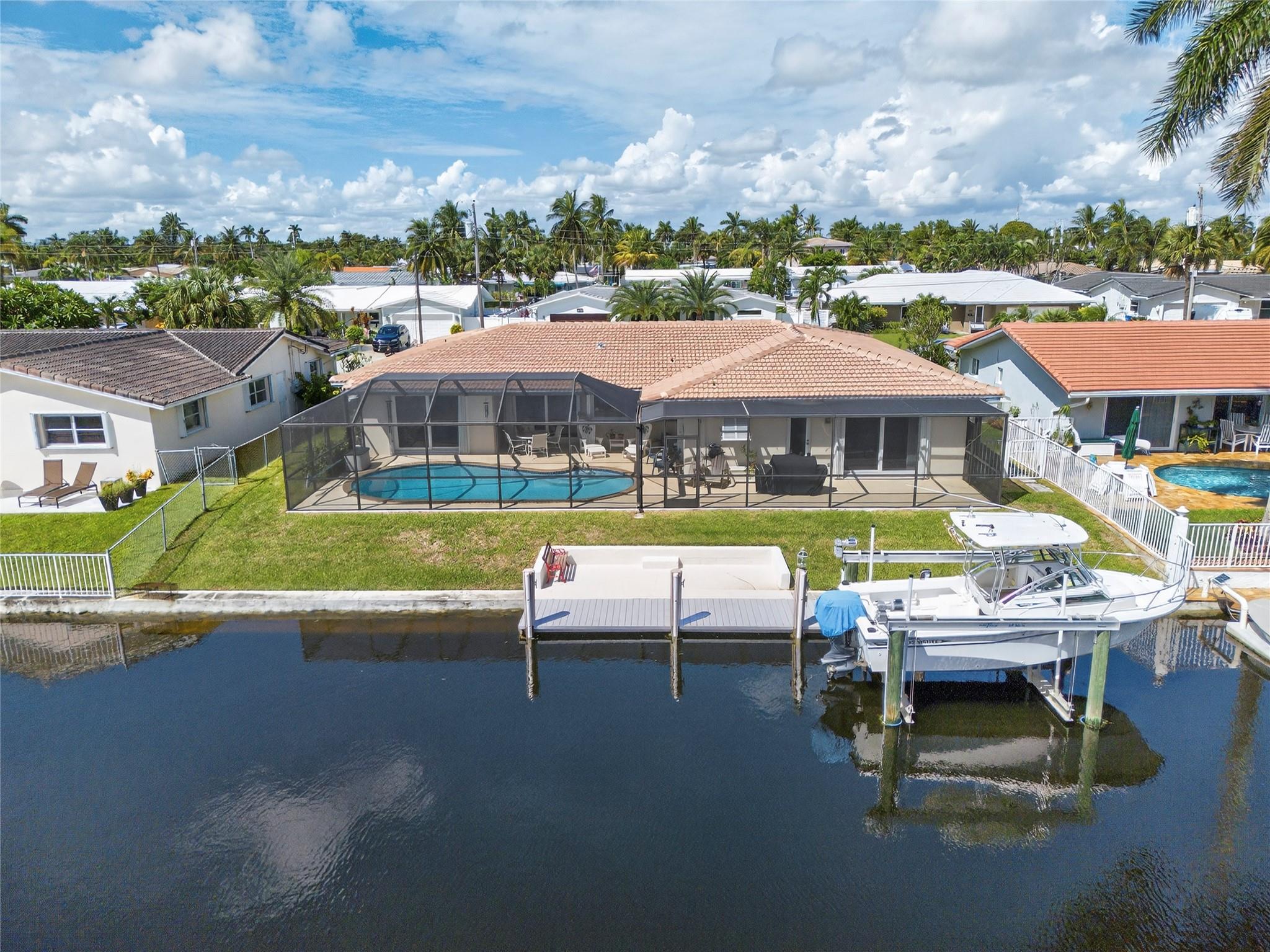 Well maintained 4 bedroom home with 2 original bathrooms, 2 car garage, screened pool and 80 feet of water frontage, one fixed bridge to ICW.  Dock is composite and includes boat lift.  Roof recently replaced in 2024, split package A/C units.  Interior & exterior electric panels updated 2018 including generator hookup.  Impact windows and doors.  Kitchen is older but not original, opens to family room.  Formal dining room in living room.  Fourth bedroom connects to primary suite, ideal as an office, gym or nursery.