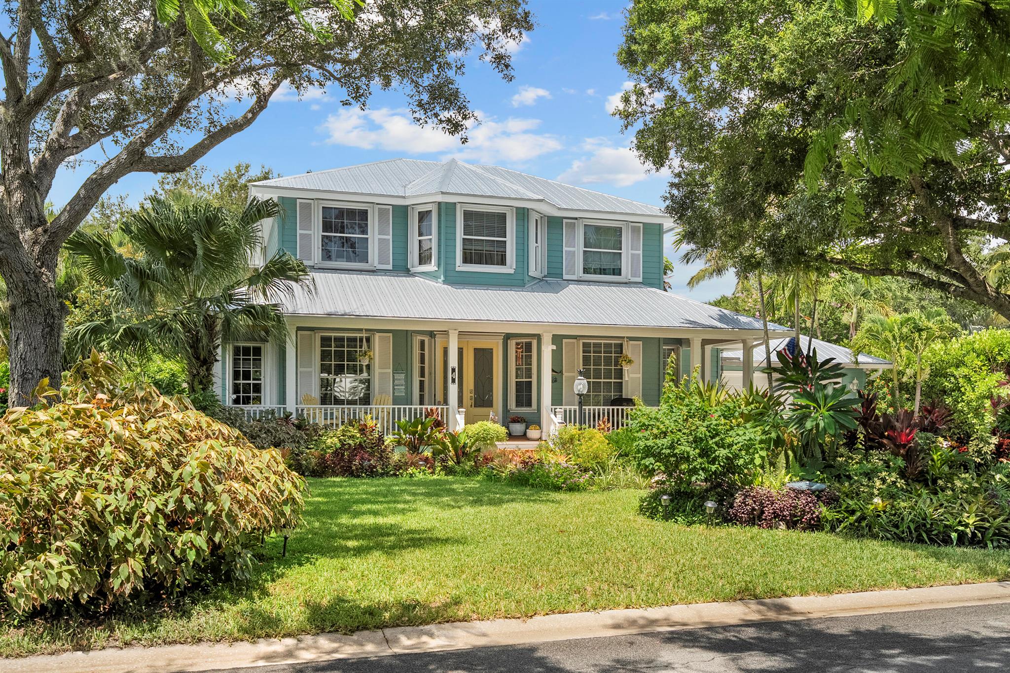 Nestled on a private, tree-lined street in Sewall's Point, this charming 4-bedroom + den, Key West-style home offers a perfect blend of comfort and tropical elegance. The spacious open floor plan features a downstairs primary suite, ensuring ultimate convenience and privacy. A wrap-around front porch invites you to relax and enjoy the serene surroundings. The backyard is a true tropical oasis, complete with lush landscaping and a stunning pool area, perfect for entertaining or unwinding. Inside, enjoy a beautifully updated kitchen, primary bath, and guest bathroom. With a newer metal roof, full accordion shutters, and energy-efficient solar panels, this home combines luxury and sustainability.