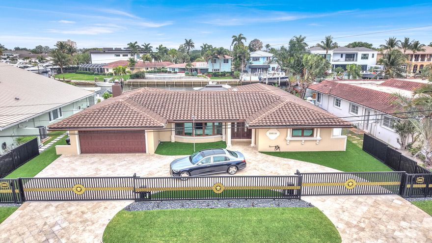 Indulge in the pinnacle of South Florida waterfront living with this exceptional 3-bedroom, 3-bathroom residence in the prestigious enclave of Venetian Isles of Lighthouse Point. Perfectly positioned along a serene canal, this home blends refined elegance with effortless indoor-outdoor living, offering a lifestyle reserved for the most discerning buyer.  Step inside to discover a thoughtfully designed, open-concept layout adorned with marble and rich hardwood flooring, creating a seamless balance of sophistication and warmth. The expansive living spaces are ideal for both intimate gatherings and grand entertaining, highlighted by a custom wet bar that elevates every occasion.  The primary suite is a private sanctuary, featuring a spacious walk-in closet and a beautifully appointed ensuite  bath, designed for ultimate comfort and relaxation. Additional guest suites provide ample accommodations, each offering privacy and style.  Outdoors, a resort-style oasis awaits. The meticulously curated backyard showcases a heated, sparkling pool, an above-ground spa, and a fully equipped summer kitchen with BBQ—perfect for entertaining under the South Florida sun. Lush landscaping and premium turf enhance the ambiance, while multiple lounging areas invite you to unwind in total privacy.  For boating enthusiasts, this property is truly unparalleled. Boasting 100 feet of prime waterfrontage, a private dock, and direct canal access just moments from the prestigious Lighthouse Point Yacht Club, you're only a short 15-minute cruise to the open ocean via the Hillsboro Inlet. Enjoy the ultimate boating lifestyle—dock-and-dine at local favorites like Nauti Dog Marina Cafe for a perfect Sunday brunch by water.  Additional highlights include a 2018 roof and a striking motorized designer gate, delivering both peace of mind and elevated curb appeal.  This is more than a home—it's a statement of luxury waterfront living in one of South Florida's most coveted boating communities.