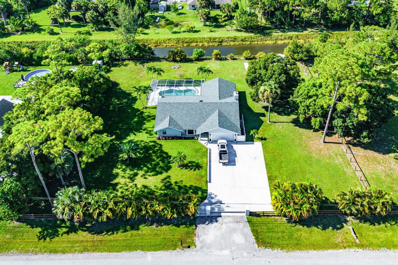 This one is a Loxahatchee BEAUTY! Lucky for you this is a one owner home and the pride of ownership shows the moment you pull in the driveway! Home sits on a gorgeous paved road and an even better large concrete driveway. Fully fenced in with a large 20ft entry gate this will certainly impress the crowd at the family get togethers. Peace of mind awaits with a BRAND NEW ROOF(2024), new designer inspired paint throughout, new fixtures and hardware and the AC is less than 5 years old! Not to mention brand new water and scratch proof LVP flooring throughout the entire home, the pool was recently rescreened, and the water system was just fully updated in 2025! Bring all your toys and animals and start your Lox Life living this year! What are you waiting for? Schedule a tour today!