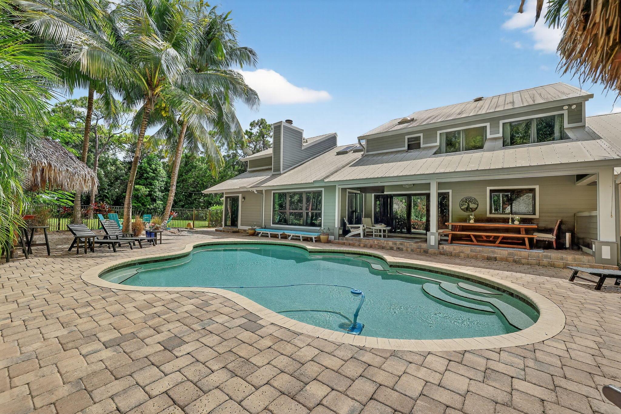 Live, work & play in your own tropical oasis! Nestled on over 1.5 lush acres in the heart of Palm City, this beautifully updated home features 5bed/3.5bath/3car, den & office spacious media room with closet and 2 gym studios. Enjoy over 5400+ sq ft of living space with room for everybody! Upgrades include impact windows and doors throughout, updated open kitchen with large island, quartz countertops and high-end appliances with master suite on main level with own sitting area. Step outside to your private paradise complete with tiki bar, grill & TV, cabana bath & saltwater pool with fire pit, perfect for year-round entertaining and relaxing in the Florida sunshine. Great location close to A-Rated schools, golf, tennis, I-95, Turnpike, fine and casual dining, beaches and PBI Airport.