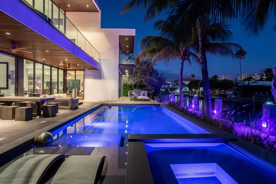 This Stunning architectural masterpiece features waterfront freedom with no bridges to Intracoastal Waterway. A soaring great room ceiling with extensive glass is the immediate impact point upon entry with views the tropically landscaped  pool and patio with a dual wave runner lift and boat 40 ft mooring area. The kitchen with central island/seating services an open dining and family/media area. The first floor ensuite bedroom is currently the media room. The second story primary bedroom suite accesses two covered balconies. There are three additional second level ensuite bedrooms, two of which have balcony access; one is currently being used as an office. A spiral staircase connects the second floor covered patio with fire pit to the pool. See MORE for additional details