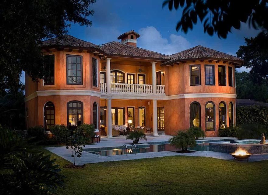 Exquisite Tuscan-Styled Waterfront Estate with Private Beach! If your dream is to live in a large waterfront estate that reminds you of the gorgeous homes of Tuscany, Italy, this is the home for you.  This gracious Hypoluxo Island estate occupies a large 18,731 SF lot and features 5,900 SF of interior living space that includes 6 bedroom  and 5.5 bath. The magnificent brick-paved entryway through electric wrought iron gates leads to the 3 car garage and the pillared front doorway into the home.  Step into another time and place with the magnificent entry featuring a spectacular spiral staircase, marble floors, soaring ceilings capped with a custom mosaic dome, and an incredible open floor plan. You'll love the charm of the fireplace that graces the living room as well as having the area bathed in natural light from the beautiful west facing windows and doors that provide peaceful views of the Coastal waters. The large center-island gourmet kitchen area features a hooded gas range with custom-tile backsplash, a spacious horseshoe shaped counter area with raised breakfast bar, stainless steel appliances, custom solid wood cabinetry, a casual dining area in the kitchen has views of the landscaping through the French doors that open to allow fresh air in during seasonal weather.  There's a fabulous family entertainment room just steps from the kitchen featuring arched windows with backyard and waterfront views. The large formal dining room with coffered-box ceiling makes easy service for guest dining and entertaining.
The Master suite located on the main floor features a coffered ceiling, custom fireplace, arched windows with water views and French doors that lead to a tiled patio with a tongue-in-groove wood ceiling and panoramic views of the dock and Intracoastal Waterway. The Master Bath has an oval-coffered ceiling with recessed lighting, dual sinks with custom faucets, a step in Roman tub with whirlpool spa jets, and a separate large glass-enclosed shower. The upper-level features beautiful wood flooring along the hall walkway that overlooks the entire lower level and leads to the additional bedrooms in the home.    The beautifully landscaped backyard features a wrap-around Cool-Deck walkway and custom designed oversized pool and spa that overlook wide-water views and scenic sunsets.  You can walk a few steps from the pool to your own private beach to enjoy the sand and salt water of the Intracoastal Waterway.  For outdoor entertaining, the exquisitely tiled and covered lanai features a full summer kitchen with hooded gas oven and grill with tiled backsplash.