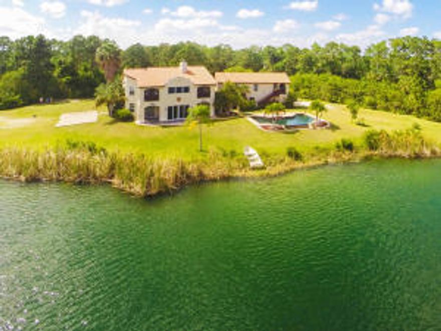 Welcome to this luxury 6.95 acreage compound also being offered with adjoining parcel totaling close to 14 acres at $875k. This lifestyle southwestern mission style masterpiece home is uniquely one of the best values in acreage properties in the Jupiter area. Drive up to this lovely private lakefront home and enter through one of a kind Incan mahogany hand carved double doors to soaring ceilings oak and Iron curving staircase. The charming custom country kitchen offers professional stainless steel appliances including propane gas stove, walk through the home on Italian porcelain and natural slate tile flooring, look up to unique and beautiful clerestory stained -glass church windows in the foyer and the great room which also offers a fireplace that was built with old Chicago bricks by