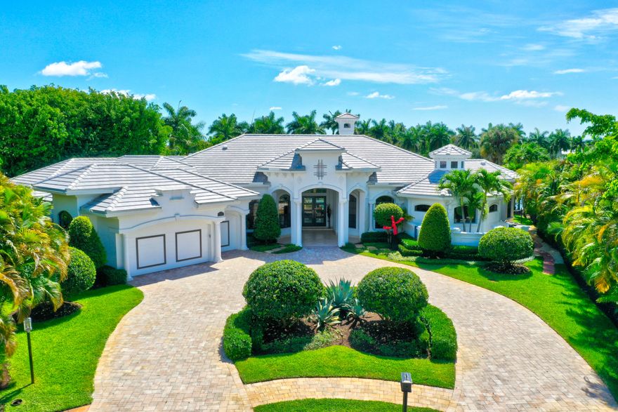 This Mediterranean style home is an architectural delight. Situated on a very private, pie-shaped lot at the end of a cul-de-sac. The expansive resort-stye pool area offers scenic views onto the lake, nestled between luscious palms trees with plenty of green space. 4 bedroom/2 office/6.5 bath, 2004 custom built home offers 5,520 sq. ft. ideally divided into separate wings; Master Bedroom wing, features an expansive master suite with his / her baths, overgenerous closets and intimate retreat off the bedroom; a great space for an office or private dressing room. The Guest wing offers 3 spacious ensuite bedrooms, all with beautifully appointed baths and walk-in closets w/ custom shelving. 3 of the homes bedrooms enjoy their own private patio courtyards, accessed by French doors (Roof 2020) The Wings of the home are connected by a grand formal great room, formal dining room, office, family and morning room, large bright kitchen, butlers pantry, separate bar bridging the dining room with the kitchen, elegant powder room and full cabana bath with shower. Following the spacious laundry room is the 2.5 car garage, with cabinetry and plenty of storage space.
The open and bright main living area enjoys floor to ceiling windows providing breathtaking views and tons of natural light right as you walk in, 24" travertine flooring laid on the diagonal and a custom fireplace surround enhances the space as you enter into the home. Off to the side of the main living area is a custom built-in office with warm wood floors and a formal dining room, while the Sonos sound system is powered through the whole home. Spacious laundry room leads into the 2.5 car garage, with cabinetry and plenty of storage space.