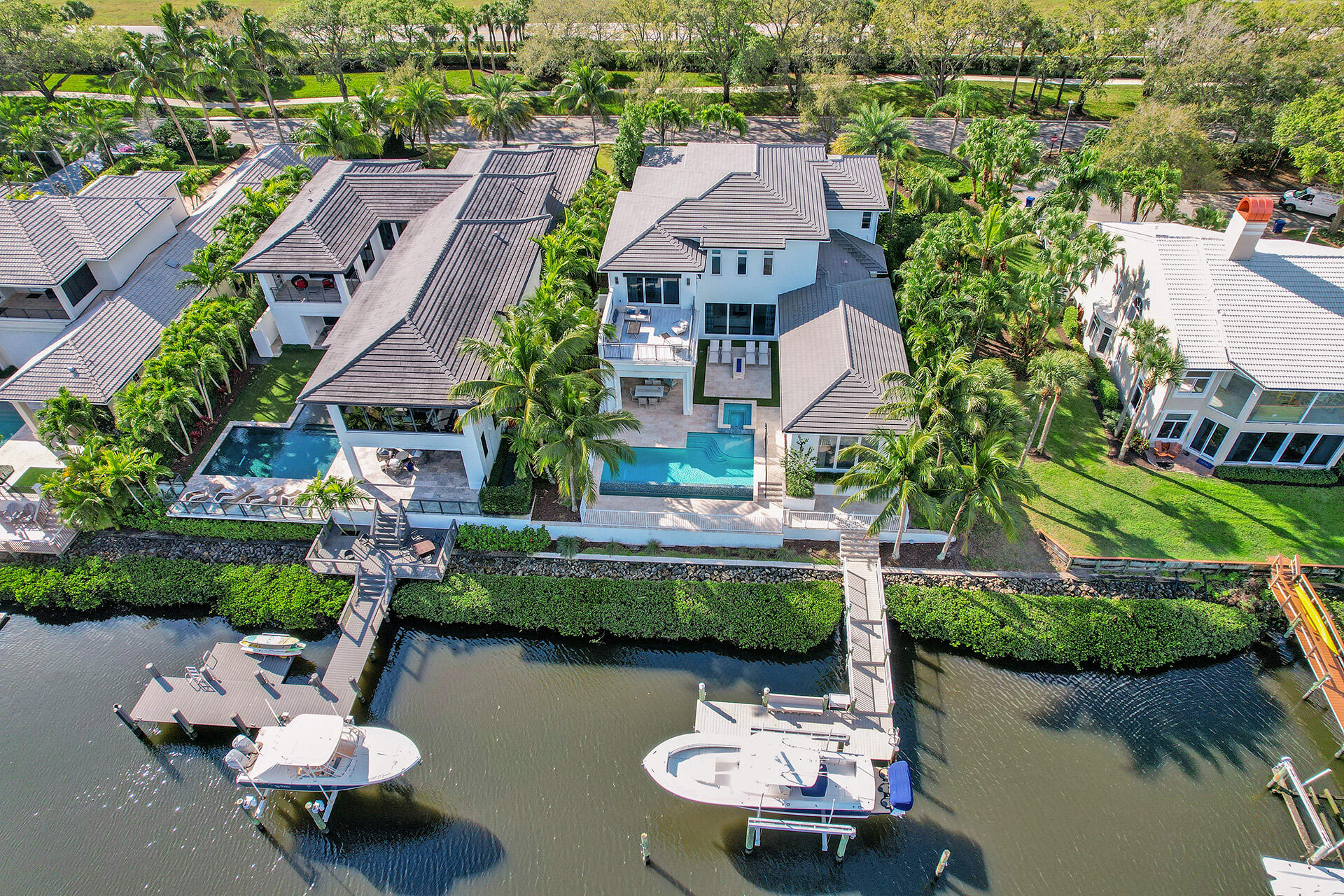 Water, water, water...Stunning vistas from this 2016 pristine estate. This is not a typical Admirals canal view! Professionally decorated and offered FULLY furnished this 2-story (with custom elevator) ,open floorplan British West Indies-styled home was designed by Mitch Kunik of Afiniti Architects. 5-bedrooms plus a full office/study(Main level master bedroom & guest bedroom).Spectacular views from the backyard are complimented by custom landscaping surrounding the 35' infinity edge pool and 8 person spa. You will feel like you are in your own oasis. Enjoy dinners under a covered Lanai utilizing the fully equipped outdoor summer kitchen & automated roll down screens or watch sunsets from the second floor Club Room and adjoining expanded terrace. The 35' dock will accommodate your 50' boat