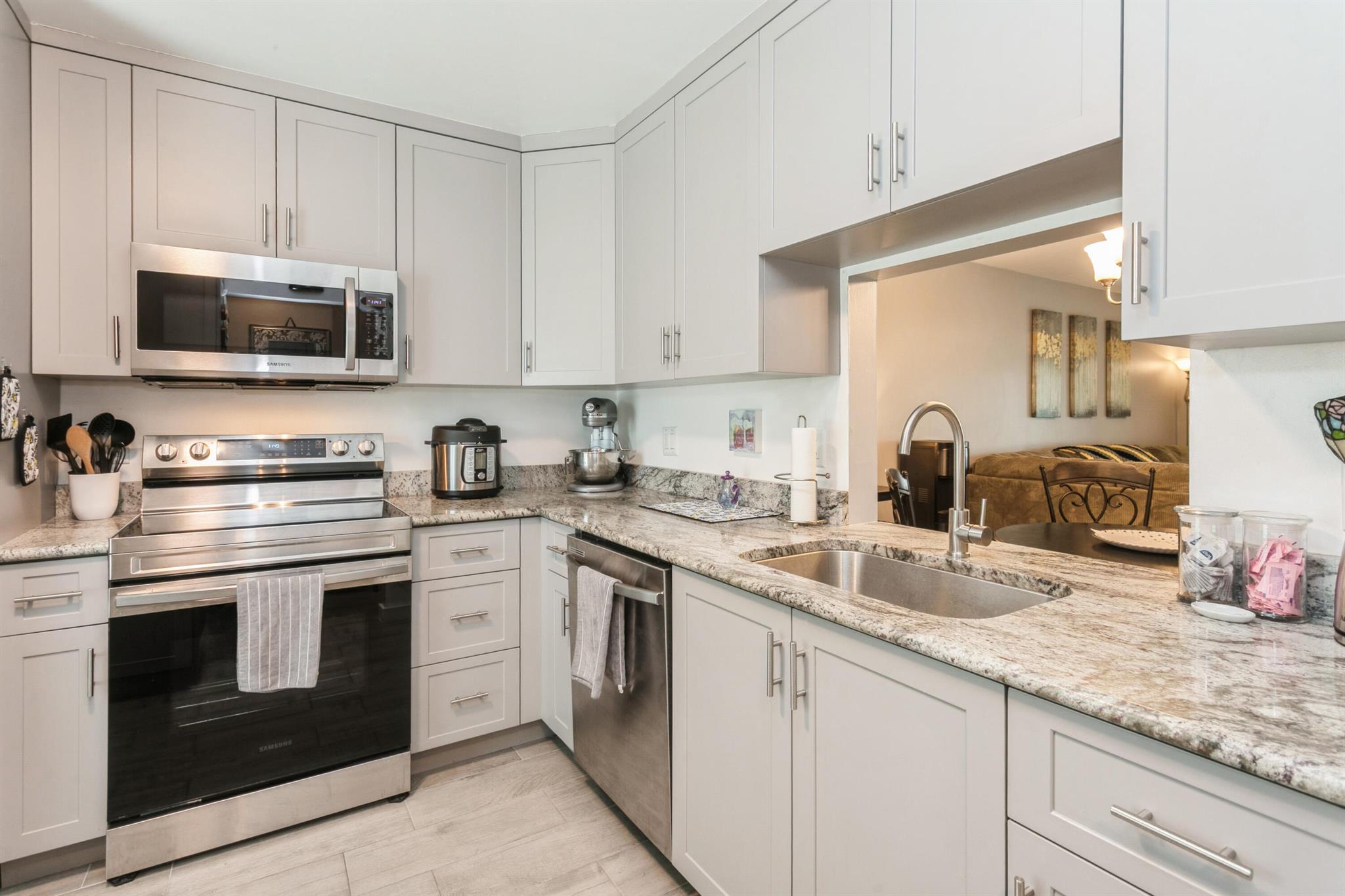 Completely Renovated! This stunning 2-bedroom, 2-bathroom corner unit features an updated kitchen with granite countertops, custom cabinetry, and brand-new stainless steel appliances. Enjoy custom lighting, ceiling fans, and plank-tile flooring throughout. Impact-resistant windows are installed throughout, and a three-track sliding glass door opens to a spacious Florida room. New LG stackable washer & dryer inside unit.Both bathrooms have been fully renovated with quartz countertops and modern vanities. The primary bathroom features a floor-to-ceiling tiled walk-in shower. Located in Covered Bridge, a 55+ community, pet friendly that allows rentals after 12 months of ownership. A short distance away from Okeeheelee Park, shopping, and access to both I-95 and the Florida Turnpike
