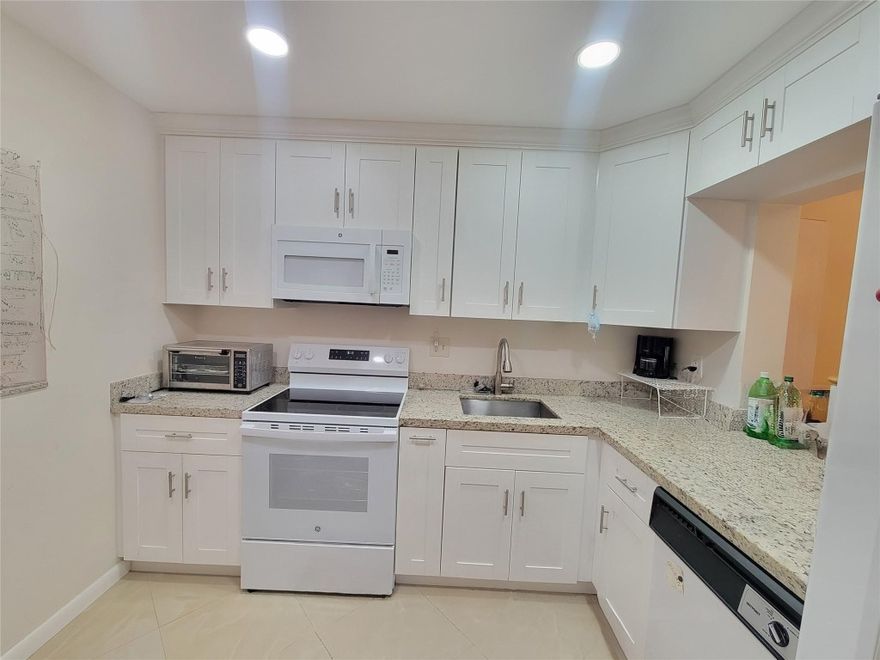 This amazing remodel 2/2 unit located on the 1st floor of 1090 sq. ft awaits you.  Fall in love with this spacious and open-concept kitchen, stainless steel appliances and quartz countertops and polished 20x20 porcelain tiles throughout including bathrooms and screen porch. Washer & dryer. Impact windows and door and upgraded electrical panel. Low maintenance fee $339/monthly. As per association Lease is allowed in this building after one year. Lots of guest parking. 55+ community with 14+ allowed.