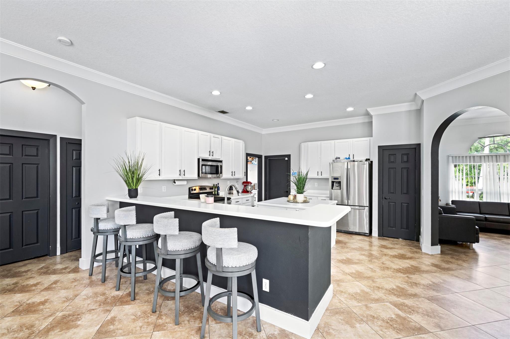 Stunning 4 bedroom, 3 bathroom home with 3-car garage, heated pool, and screened enclosure on oversized corner lot. Expansive layout with tall ceilings, hi-hat lighting, and neutral tile throughout. Bright white kitchen with Corian countertops, stainless appliances, and center island overlooking family room with custom built-in entertainment center. Multiple sliding doors bring natural light and open to the pool. Primary suite offers walk-in closet, dual sinks, and private pool entry. Huge yard with fruit trees and storage shed. Cabana bath and back bedroom for ideal guest/MIL suite. Ample parking with 3-car garage and driveway. Large fenced yard and screened patio. Centrally located near Port St. Lucie shops/food with quick access to downtown Fort Pierce, Jensen Beach, and Traditions
