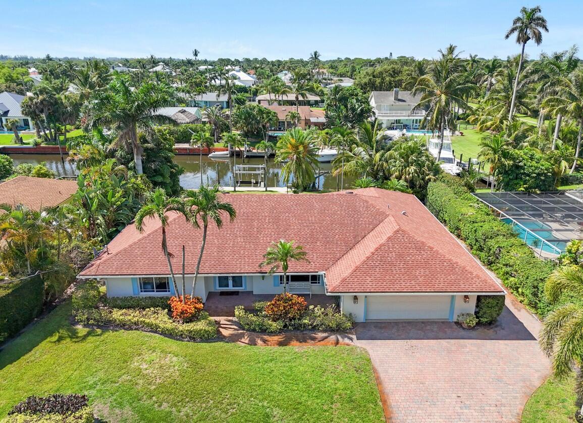 Coastal Waterfront Retreat with Southern Exposure. Welcome to this beautifully renovated coastal-style waterfront home offering the ultimate South Florida lifestyle. Situated on a spacious .32-acre lot with 100 feet of waterfront and no fixed bridges, this boater's paradise includes a 14,000 lb boat lift, seawall, and direct ocean access. Enjoy sun all day with prime southern exposure, perfect for relaxing poolside or entertaining in the expansive covered outdoor living space. The fenced backyard features a sparkling pool and lush, manicured landscaping for added privacy and charm. Inside, the light and bright open floor plan features volume shiplap ceilings, split bedroom layout, and impact windows throughout.