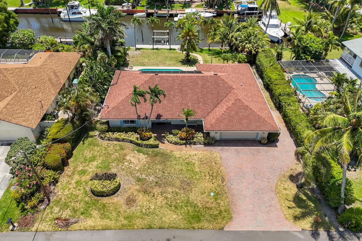 Coastal Waterfront Retreat with Southern Exposure. Welcome to this beautifully renovated coastal-style waterfront home offering the ultimate South Florida lifestyle. Situated on a spacious .32-acre lot with 100 feet of waterfront and no fixed bridges, this boater's paradise includes a 14,000 lb boat lift, seawall, and direct ocean access. Enjoy sun all day with prime southern exposure, perfect for relaxing poolside or entertaining in the expansive covered outdoor living space. The fenced backyard features a sparkling pool and lush, manicured landscaping for added privacy and charm. Inside, the light and bright open floor plan features volume shiplap ceilings, split bedroom layout, and impact windows throughout.