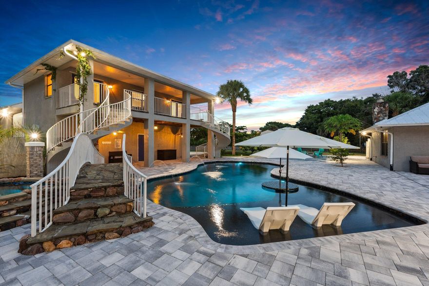 A rare find in the heart of Fort Pierce, this private 2.44-acre estate pairs timeless craftsmanship with resort-style living--just minutes from the beach. With 7 total rooms, 4 bathrooms and additional finished square footage across multiple structures. Tucked behind a gated entry and surrounded by an 6-foot perimeter wall, the main residence showcases CBS and brick construction in classic Colonial style, featuring 4 bedrooms, 3 baths, a great room with high ceilings, and a hand-laid brick fireplace. Outside, a resort-style pool and spa area invites you to unwind in true Florida fashion, complete with a waterfall, stone bridge, and sun shelf framed by swaying palms. A separate two-story guest house sits above a 56' x 36' garage with four RV-height roll-up doors, full bath, game room, and