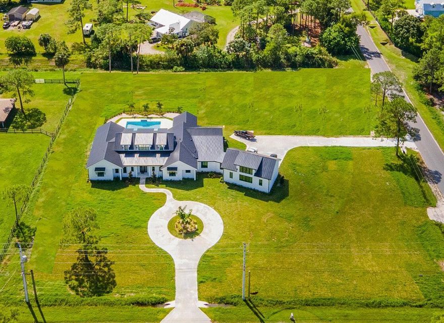 This stunning custom coastal farmhouse is a spacious single-story home offering 4,766 A/C sf of luxurious living space and 7,403 total sf. It features 4 bedrooms, 4 full baths, 2 half baths, a dedicated office, Club Room that opens up to the Covered Patio and Summer Kitchen, plus a generously sized study that can serve as a 5th bedroom. The home also includes an oversized 3-car garage with a large attic/loft. Sitting on a high and dry 2.25-acre lot in Jupiter Farms with no wetlands, this property provides ample space for a guesthouse, stables, and/or a large detached structure. It also comes with approved plans for an additional 2,000 sq ft detached garage--perfect for car enthusiasts, a workshop, or extra storage. Other features include full house Reverse Osmosis water system,