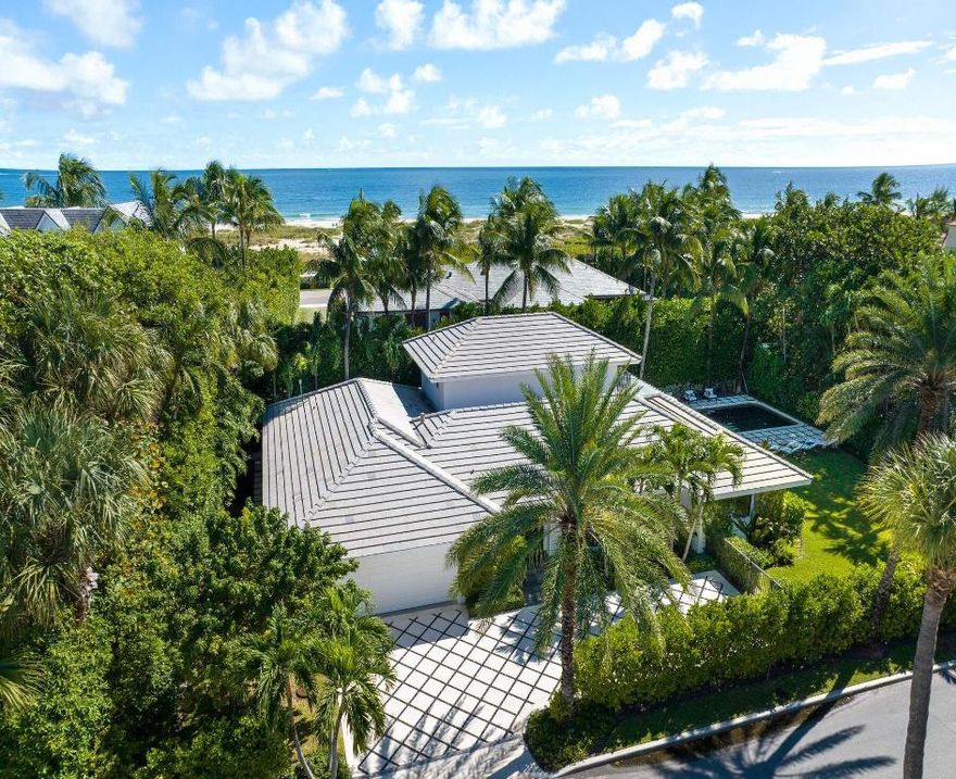 Located on a quiet street in Palm Beach's North End, this modern beach house offers 3,803± total square feet with four bedrooms and four and a half bathrooms. Set on a 12,206± square foot lot, the property features a large pool, spacious yard, and an air-conditioned two-car garage. The interior blends comfort and coastal style, with wood flooring throughout the main living areas and marble finishes in the bathrooms. The living room opens through sliding glass doors to the pool and patio area, creating a natural flow between indoor and outdoor spaces. The kitchen includes a breakfast area, full-size Sub-Zero refrigerator and freezer, double ovens, and an electric cooktop. The adjacent dining room overlooks the lushly landscaped grounds. Three bedrooms are located on the main level, each with en suite baths and closets. The primary bedroom features two walk-in closets and French doors that open to the pool. Upstairs, a private guest suite includes a balcony overlooking the pool and an en suite bath. The property features a pathway, accessible from the side yard, that leads to a private beach parcel.