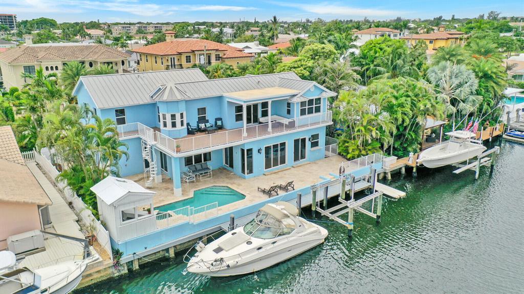 Waterfront Key West-inspired coastal living accompanies this custom-built home- with 4 bedrooms, a library/den, and a home office. This property is perfect for the buyer seeking a boating lifestyle. Minutes from The Boca Inlet with ocean access, 85 feet of waterfront, and a 50-foot dock with amenities such as a floating jet ski dock, boat lift, freshwater supply, 110 and 220 volt Electric with GFCI, and dedicated cabana bath. From the moment of entry, the soaring foyer leads to the 2nd floor and the 4 bedrooms. Downstairs the front living area can function as a library, formal living room, game room, or den. From this room is access via French doors to the oversized private office. The open main living area is fitted with natural hardwood floors throughout, and both it and the kitchen