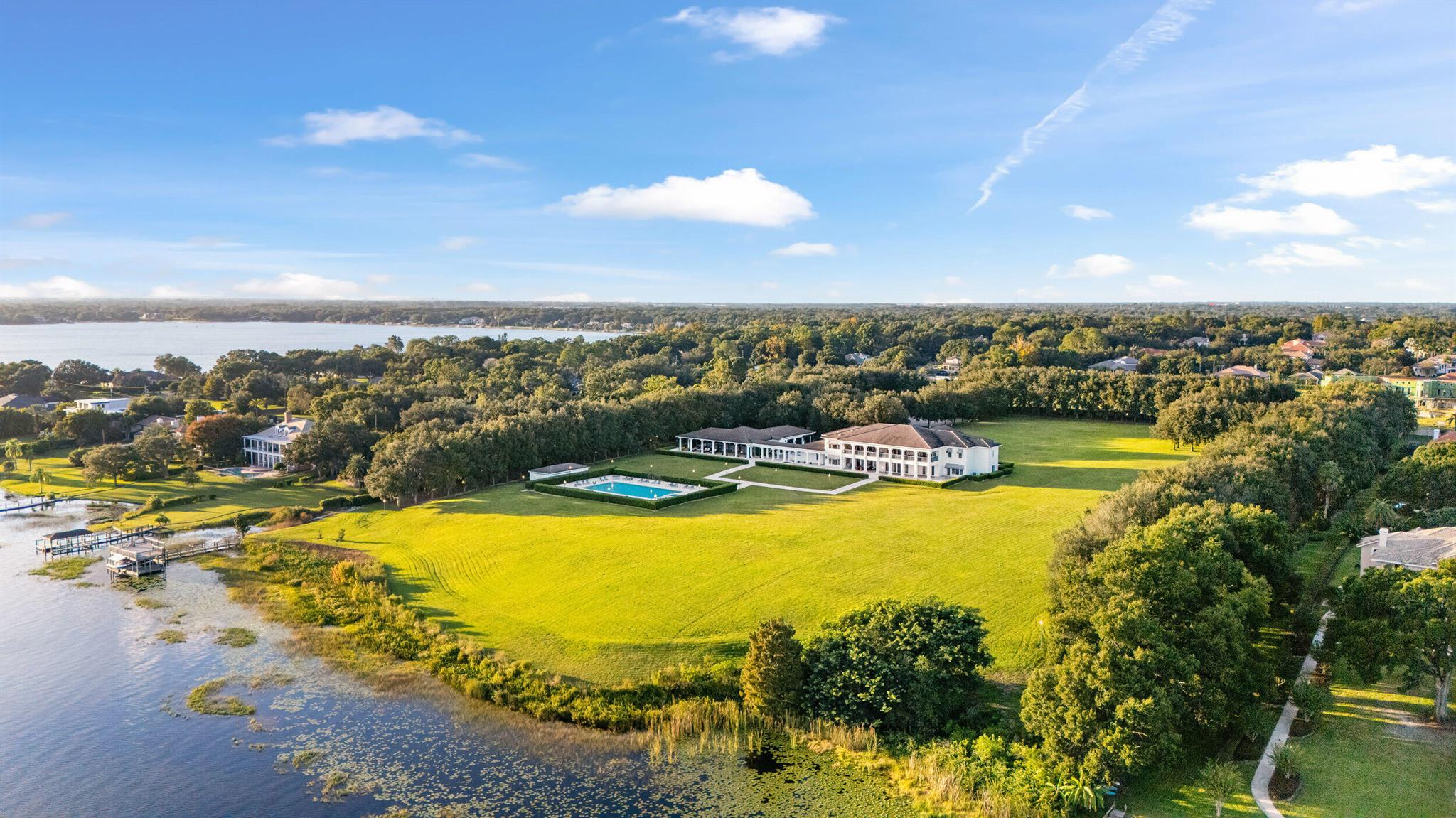 Discover this Perfectly positioned Georgian Estate situated on 12 acres (additional 6 acres available) of lakefront property with meticulously manicured grounds. This walled and gated compound includes approx 614 feet of pristine lake frontage and panoramic views on Lake Down of the Butler Chain of Lakes. The magnificent sprawling primary residence pairs classic Georgian architecture with modern amenities to achieve the ultimate lakeside retreat. Immediately you are greeted by the finest materials and finishes inside an elegant entryway which opens into a grand interior boasting a floating mahogany staircase, marble floors and paneled walls all framed by stunning Murano chandeliers. An art gallery leads into a spacious living room lined with mahogany walls and boasts expansive waterfront