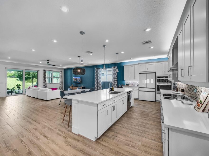 OVER $75,000 in UPGRADES! This exceptional, barely lived-in residence is located within the prestigious 55+ community of Telaro at Tradition and presents in immaculate, like-new condition. Thoughtfully curated with an extensive collection of high-end upgrades, the home offers refined elegance and effortless modern living throughout. Timeless tile flooring flows seamlessly through every room--no carpet--complementing the open-concept design that is ideal for both entertaining and everyday comfort. The chef-inspired kitchen is a true centerpiece, featuring upgraded quartz countertops, a striking designer backsplash, premium stainless steel appliances, a glass-front refrigerator, wall ovens, an induction cooktop, and custom cabinetry lighting both above and below for a warm, sophisticated glo