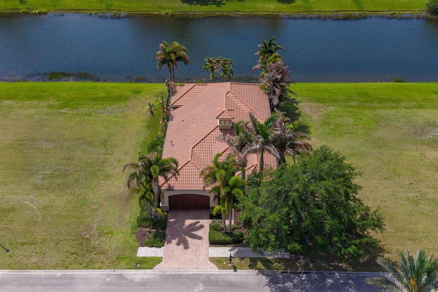 A southern view of a shimmering, freshwater lake is yours in this custom home. Marble flooring with hand-cut granite accents welcomes you into the foyer, which features a solid wood stormproof front door. 16 ft high ceilings are found in the foyer & great room. The handcrafted solid-wood entertainment center is the focal point of the great room. The kitchen features top-quality appliances, solid wood cabinets & granite countertops. The office/den features hardwood floors & overlooks the swimming pool. The master suite features 14 ft high tray ceilings & transom windows that let in all of Florida's beautiful sunshine. Two closets with custom shelving are found on the way to the open main bath. His and her vanities bracket the spa tub, a Roman shower.  Membership in the club is optional.